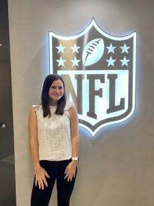Amazing student Meg Kowalski poses in front of the NFL logo