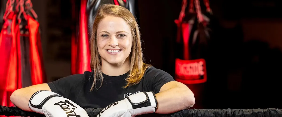 Madeline Schellman poses for a portrait in a gym wearing white boxing gloves