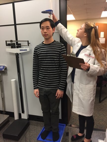 Height measurement following proper techniques. The participant's feet flat on the ground without shoes, with heels touching the back of the platform.