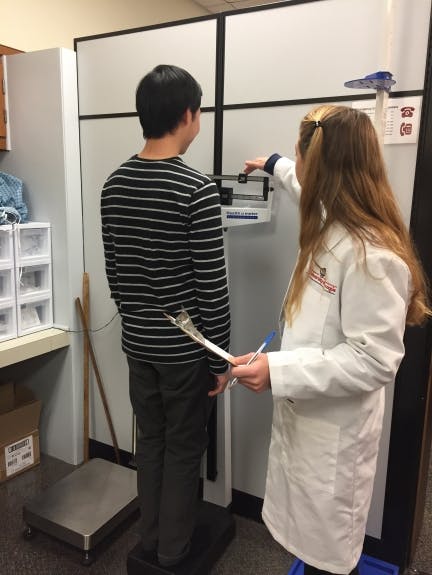 Weight measurement following proper techniques. The participant is wearing minimal clothing and no shoes.