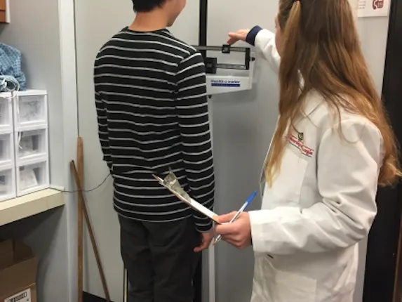 Weight measurement following proper techniques. The participant is wearing minimal clothing and no shoes.